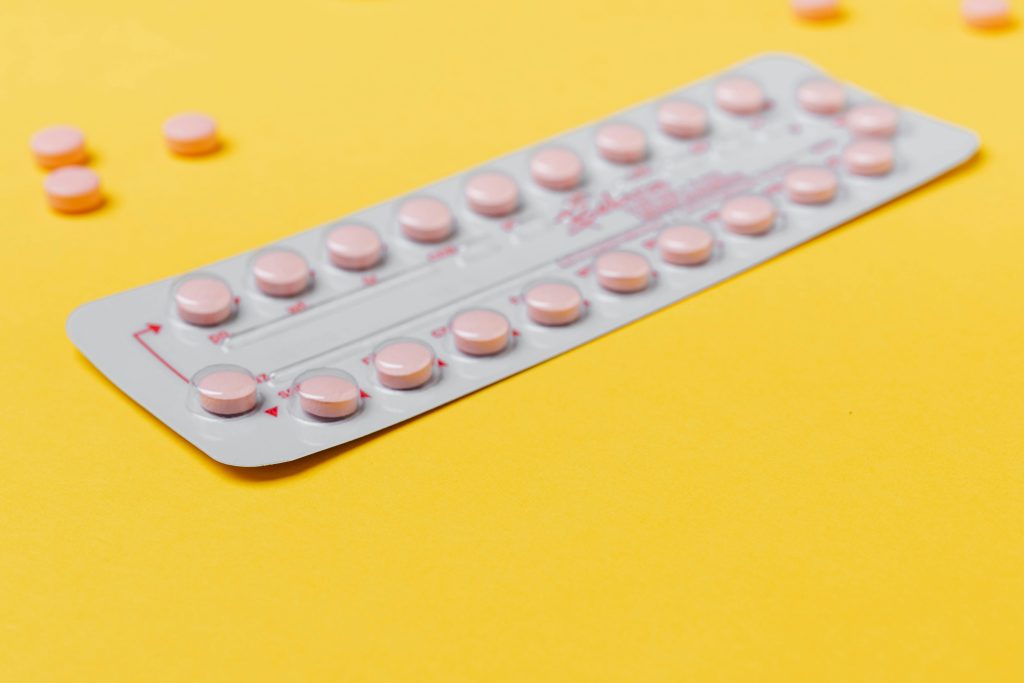 Vrouw die informatie leest over anticonceptiepil kopen in Amsterdam met medicijnen op tafel