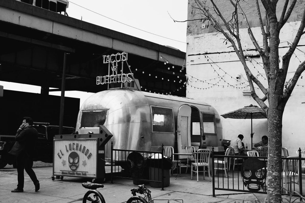 Kleurrijke foodtrucks op evenement met sissende pannen en ambiance voor Amsterdam feesten