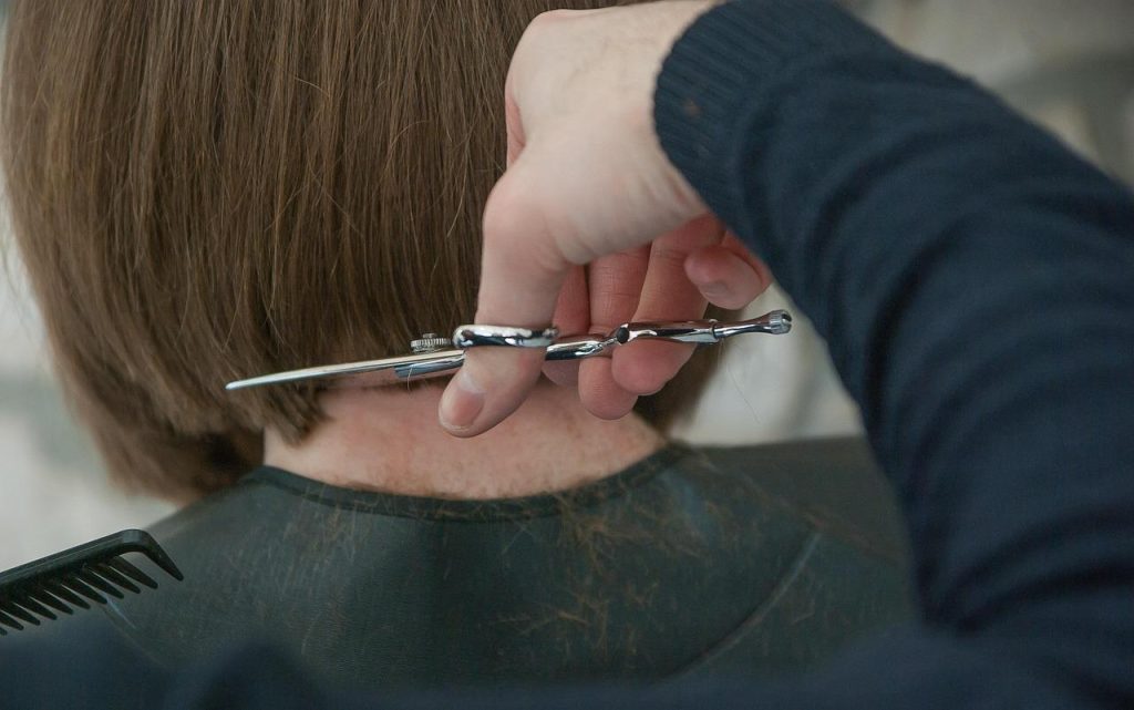 Kappersopleiding Amsterdam student oefent op klant in salon met begeleiding